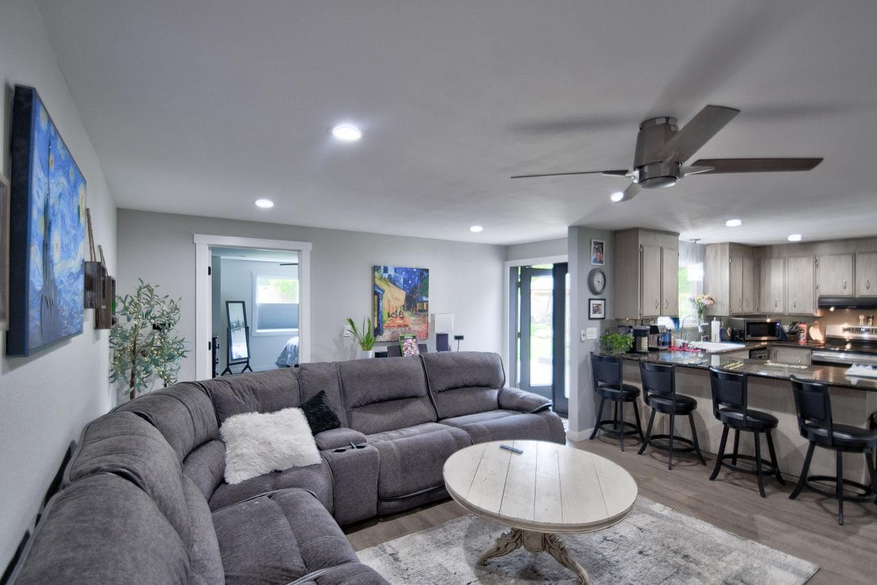 Cozy living room with gray sectional sofa, round coffee table, and open kitchen with bar seating.