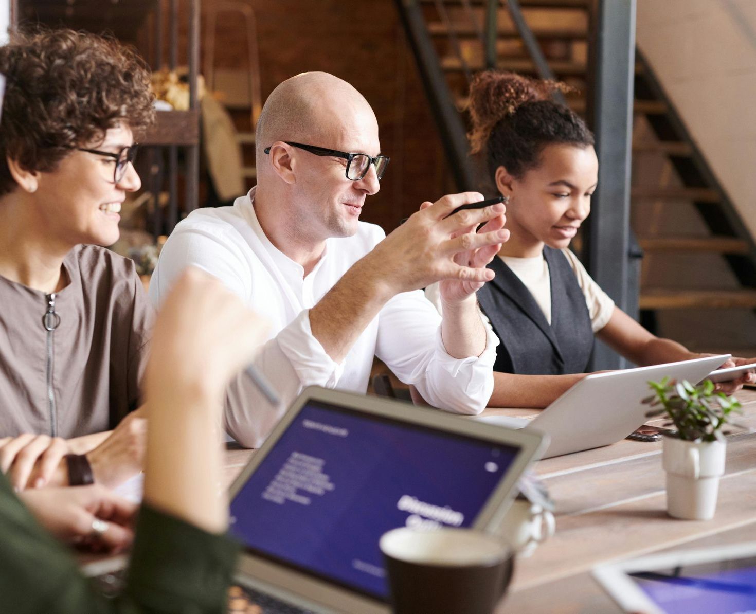 A group of people are sitting at a table with laptops and tablets.