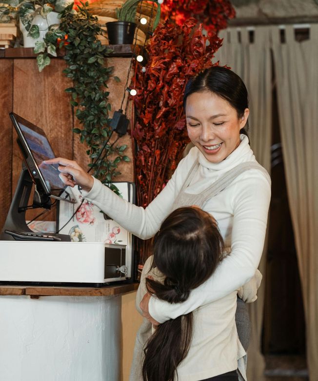 A woman is holding a child in her arms while using a computer.