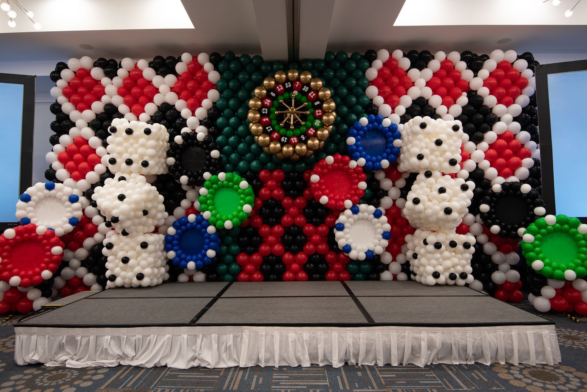 A stage is decorated with balloons in the shape of poker chips and dice.