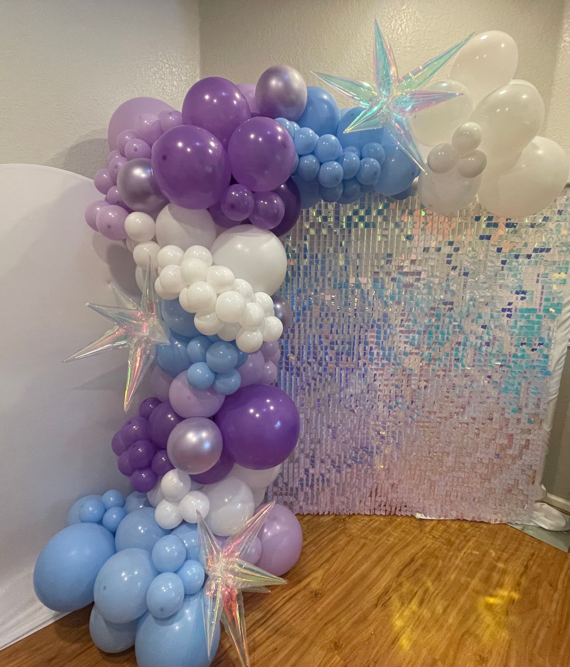 A bunch of balloons are sitting on a wooden floor in a room.