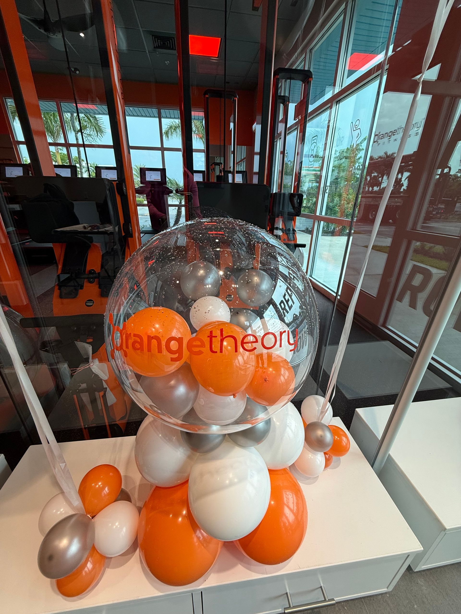 A balloon filled with orange , white and silver balloons is sitting on a table.