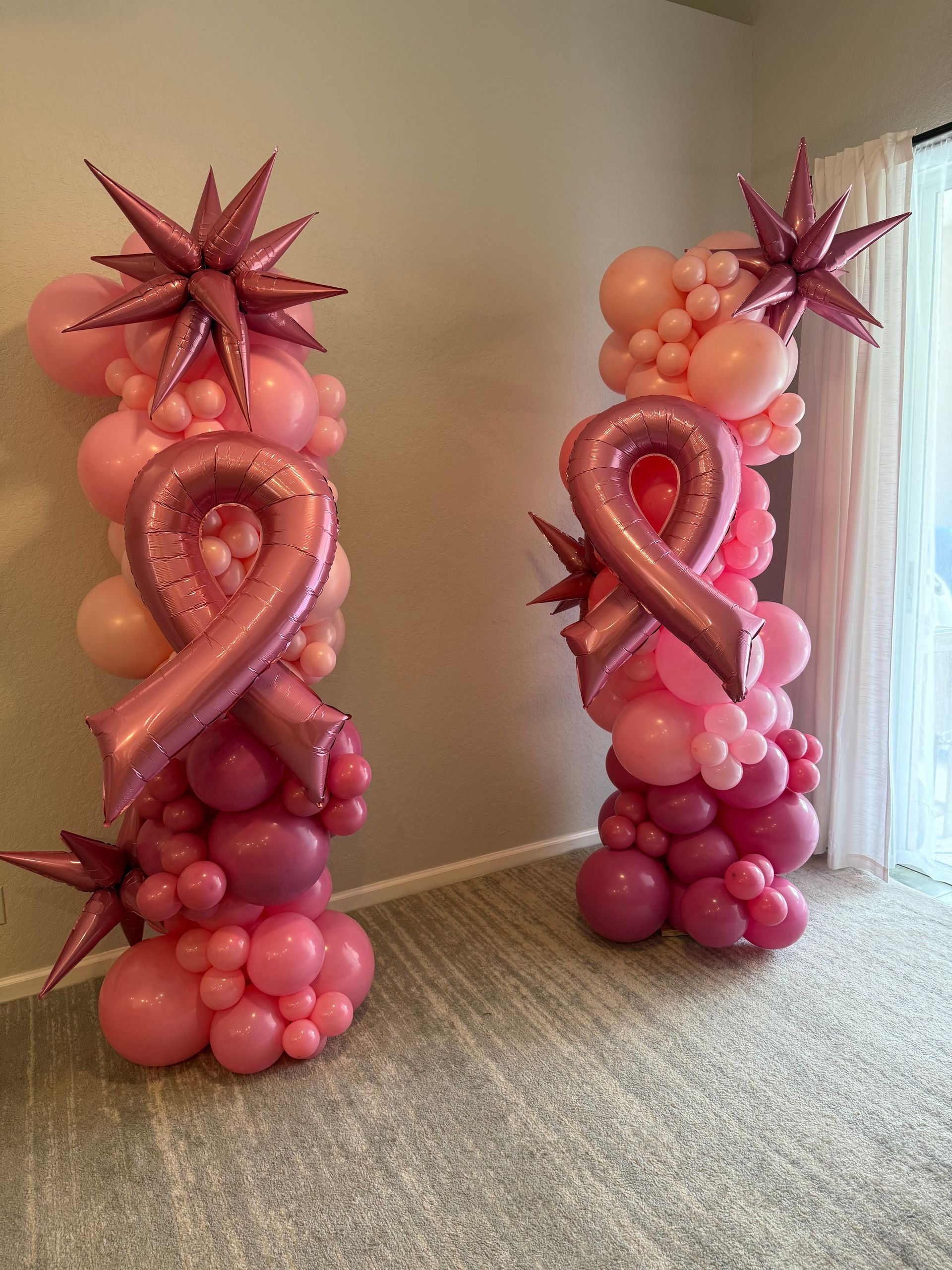 Two columns made of pink balloons with pink ribbons and stars.