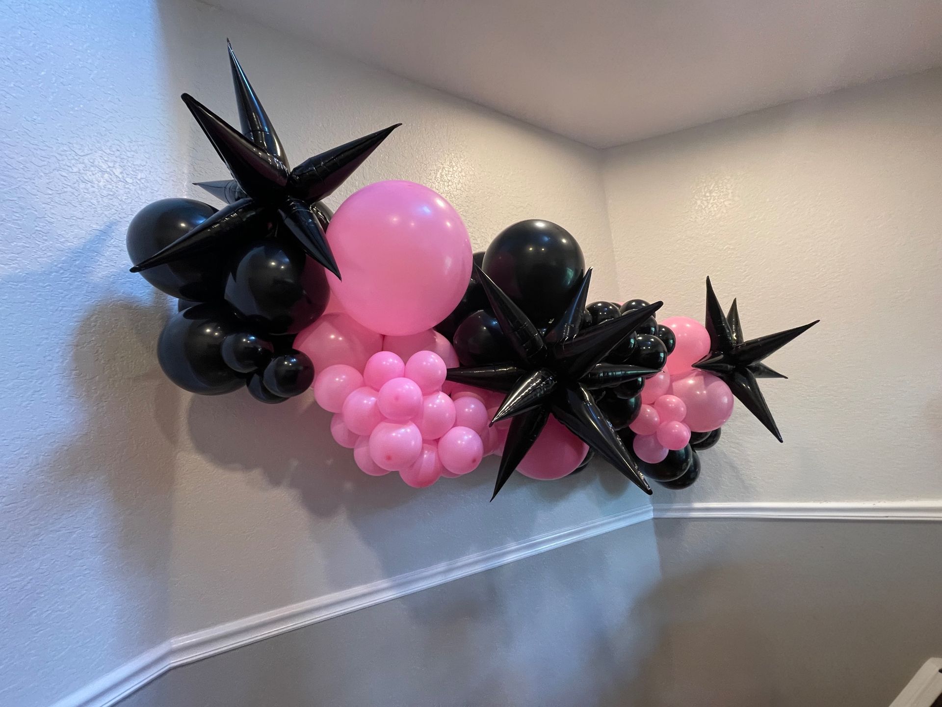 A bunch of pink and black balloons are hanging on a wall.