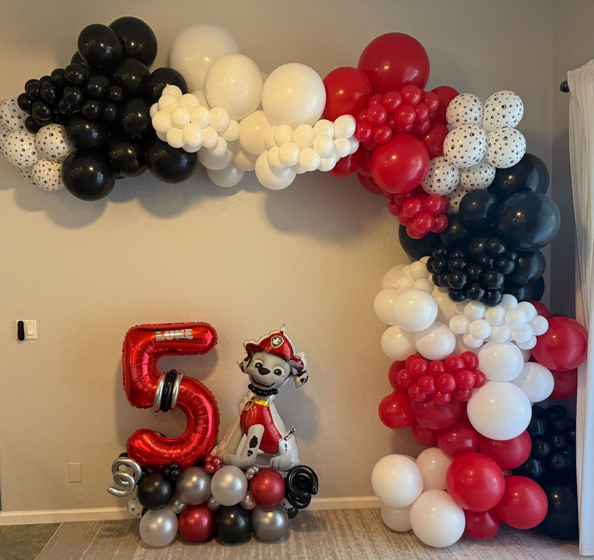 A number 5 balloon is surrounded by red and black balloons