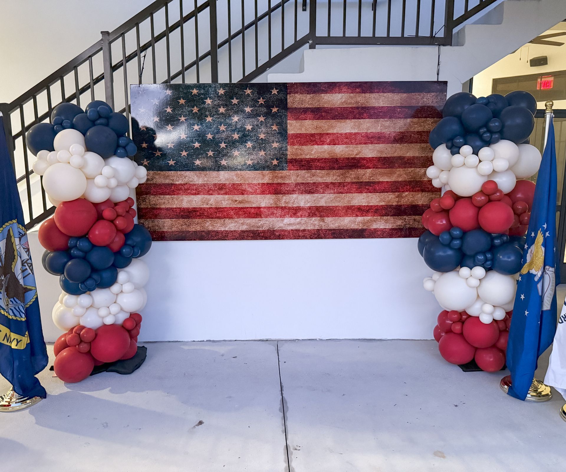 A red , white and blue balloon display with an american flag in the background.