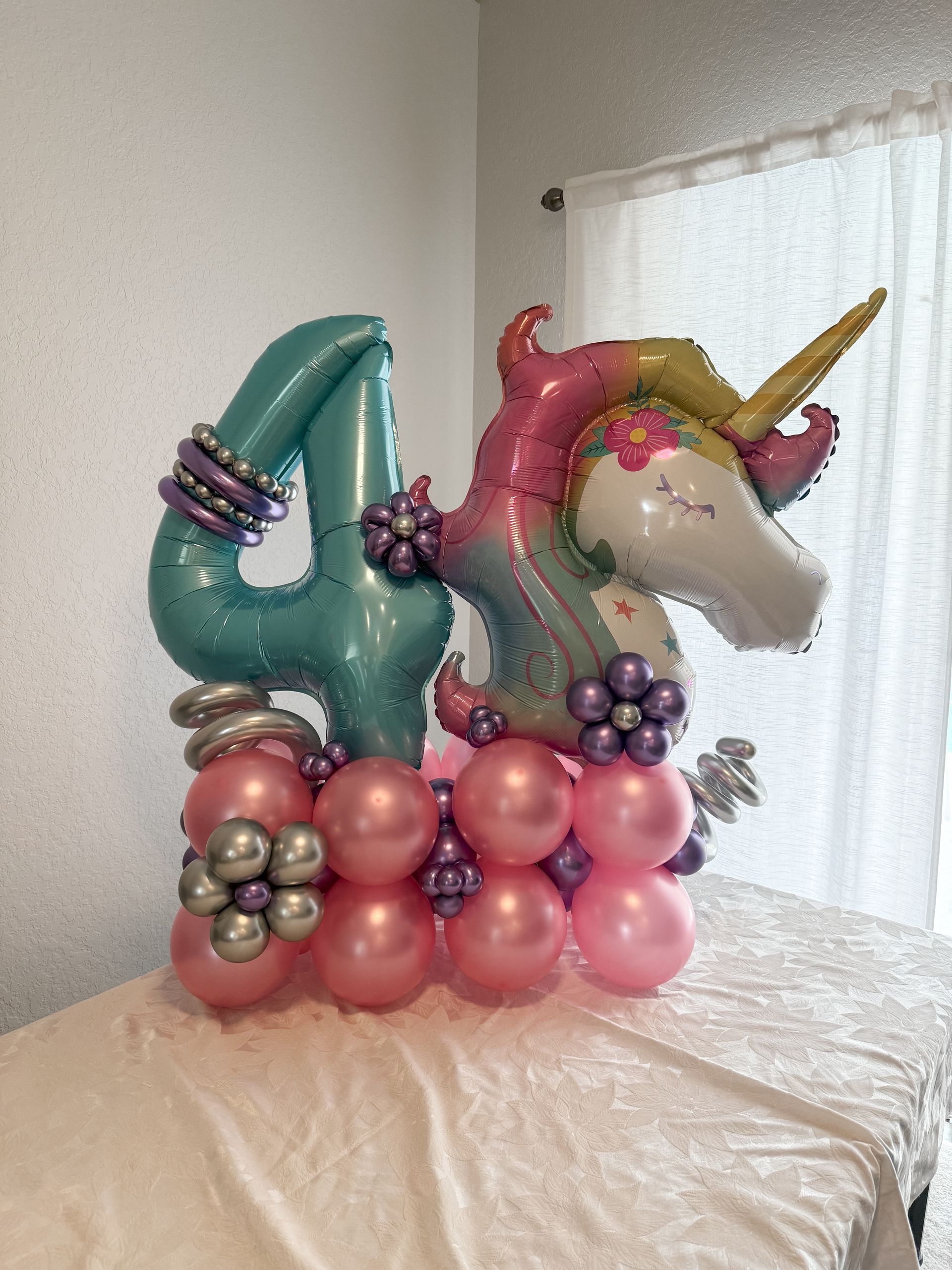 A unicorn balloon is sitting on top of a table with balloons.