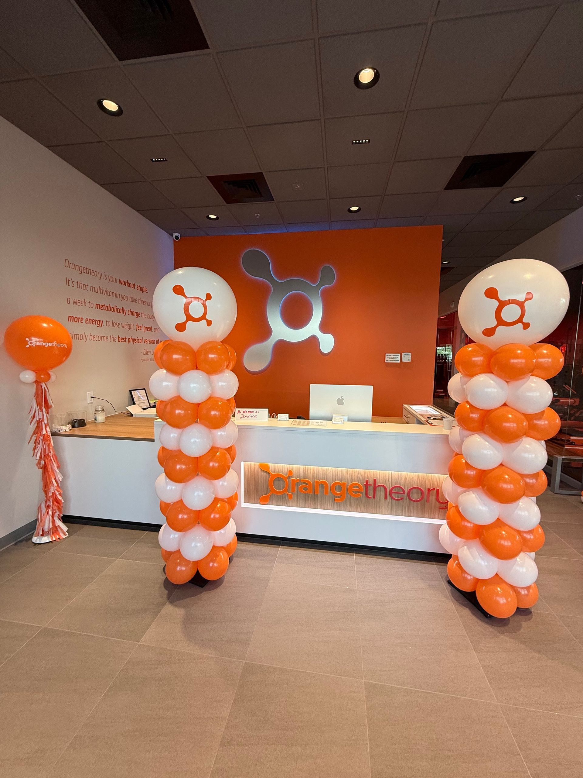 Two columns of orange and white balloons in a gym