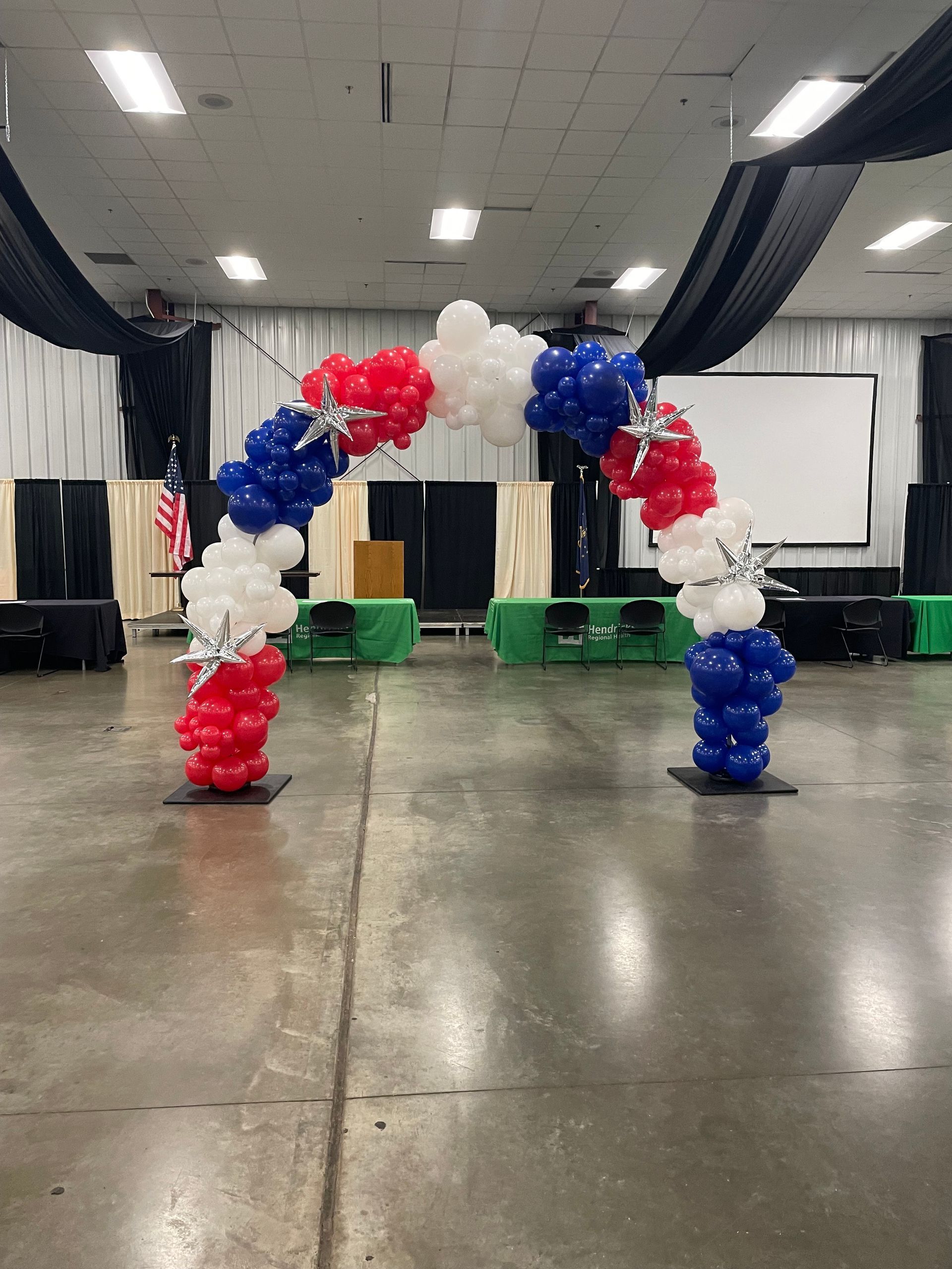 A red , white and blue balloon arch in a room