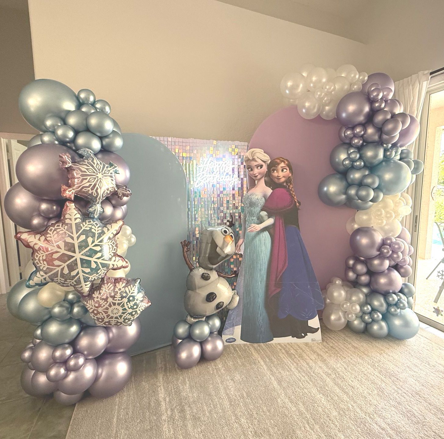 A room filled with balloons and a picture of elsa and anna.