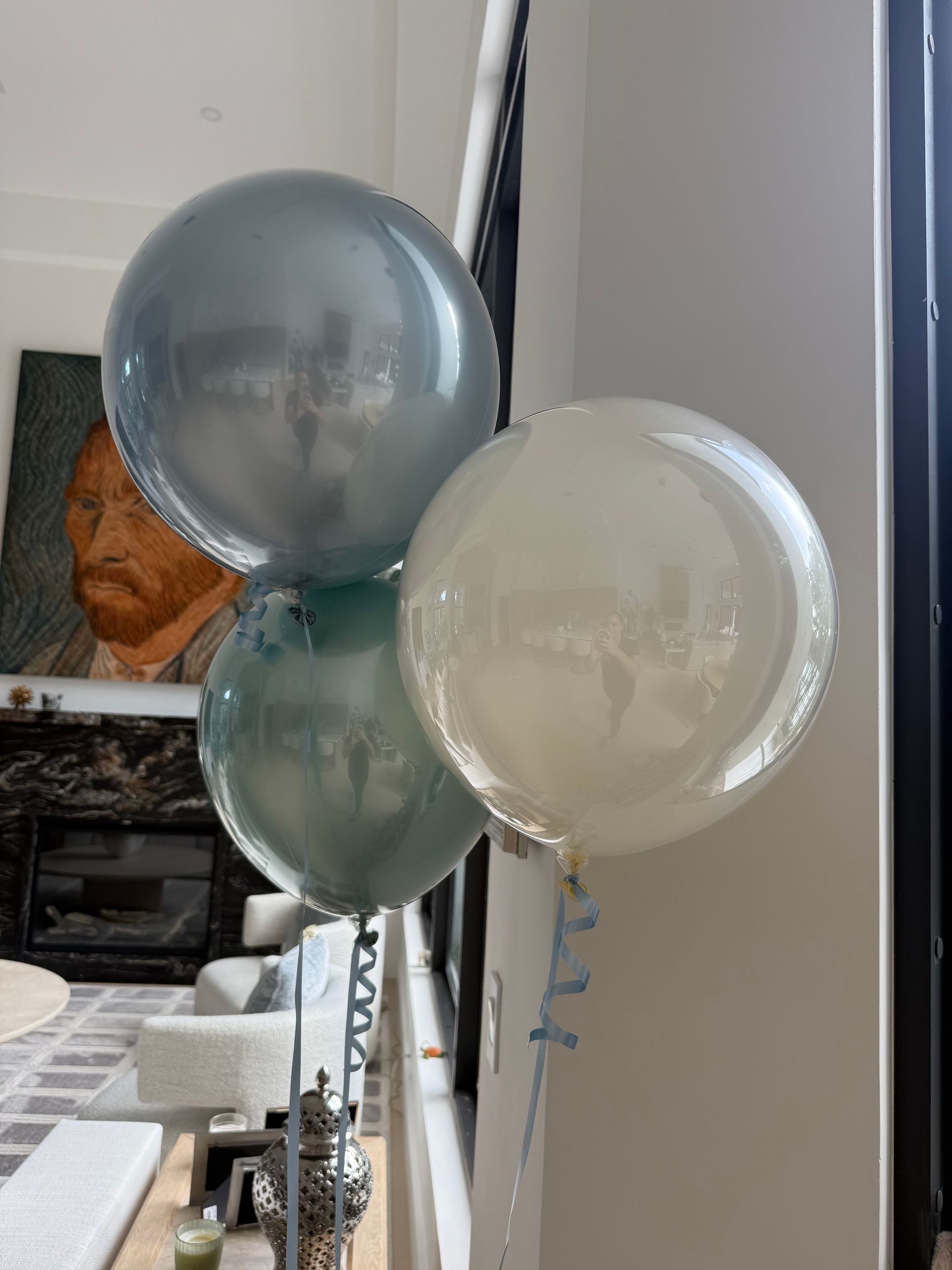 Three balloons are sitting in a living room in front of a fireplace.