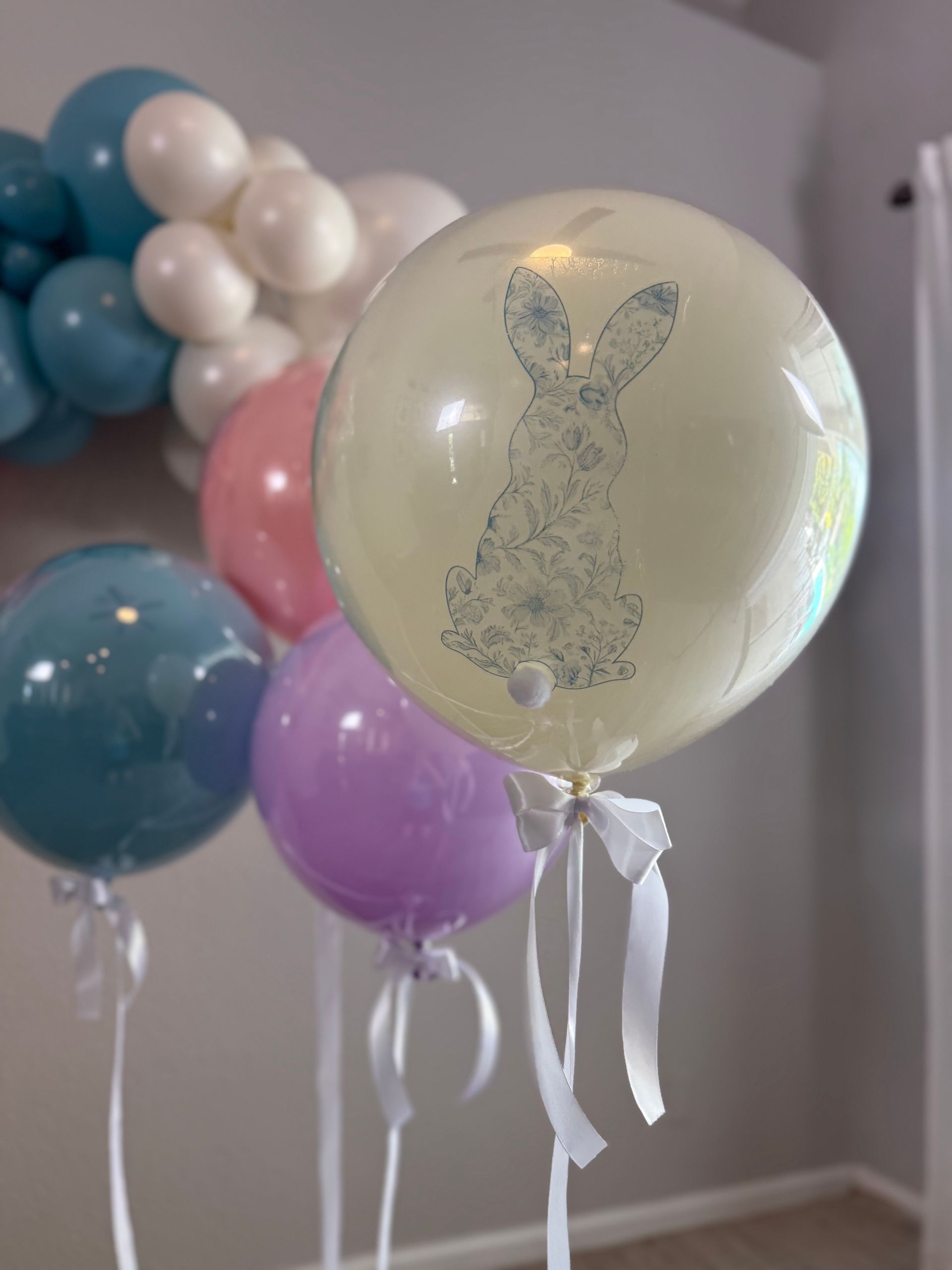 Three balloons are sitting in a living room in front of a fireplace.