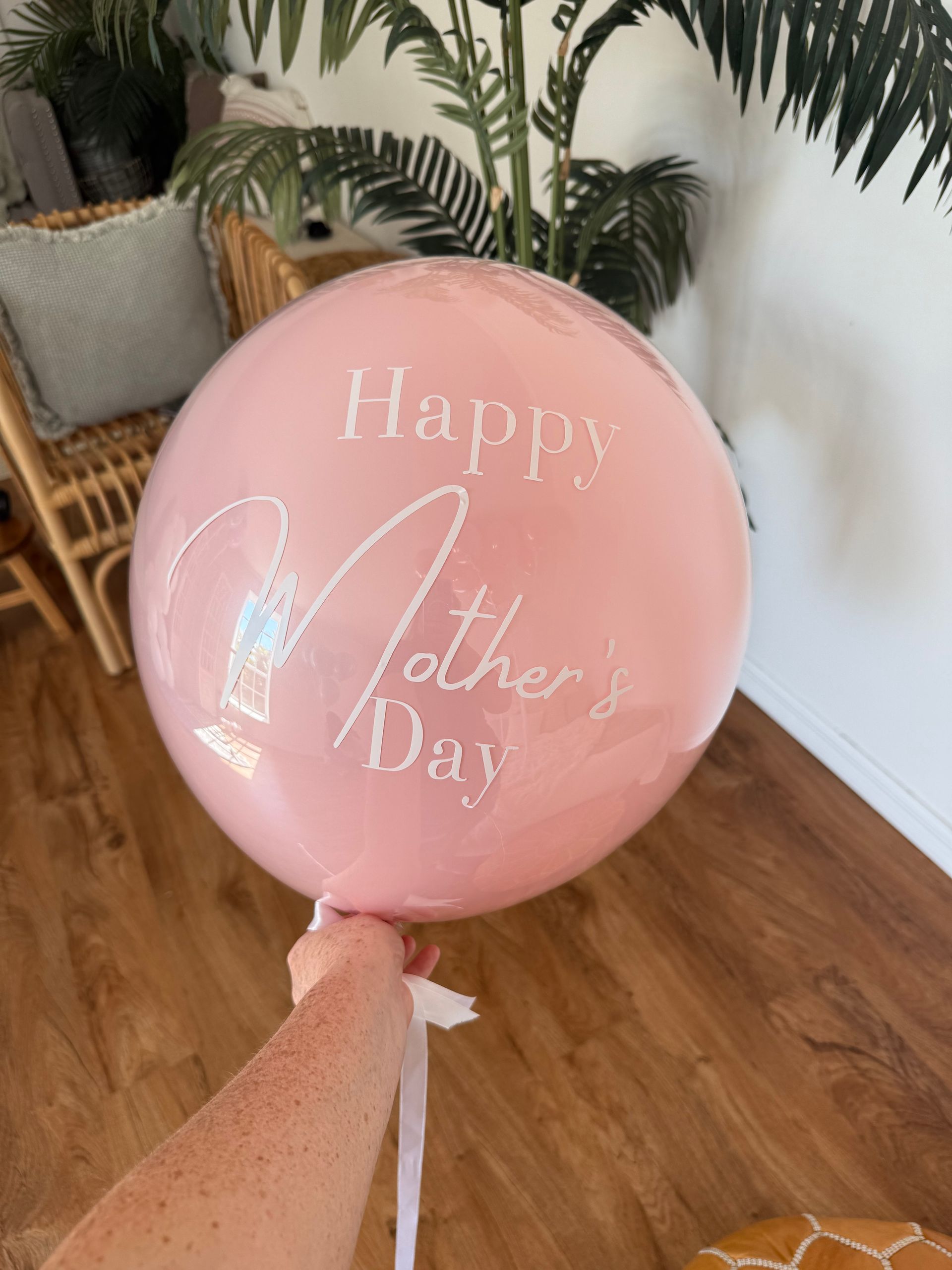A person is holding a pink balloon that says `` happy mother 's day ''.