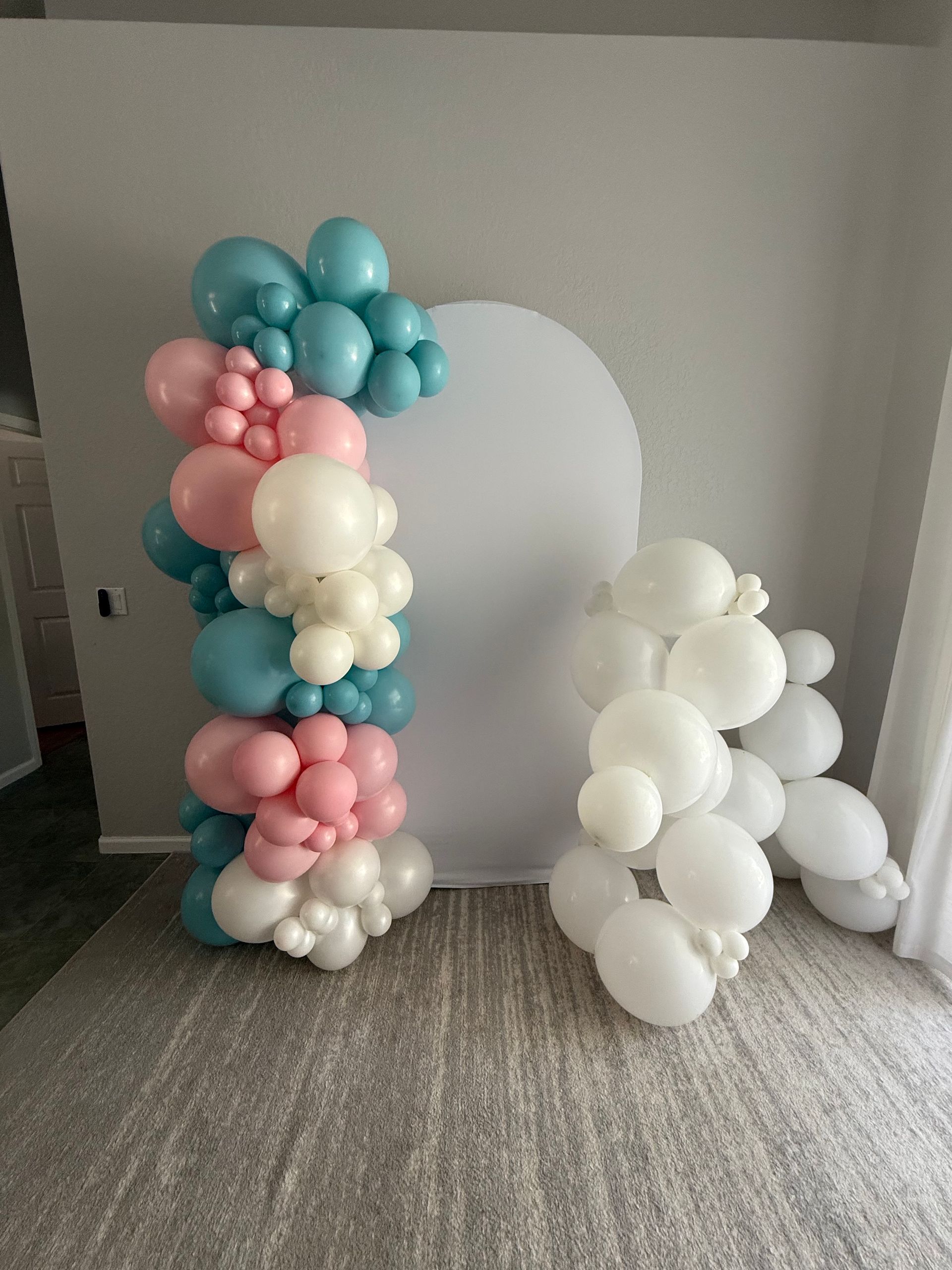 A red white and blue balloon arch in front of a store