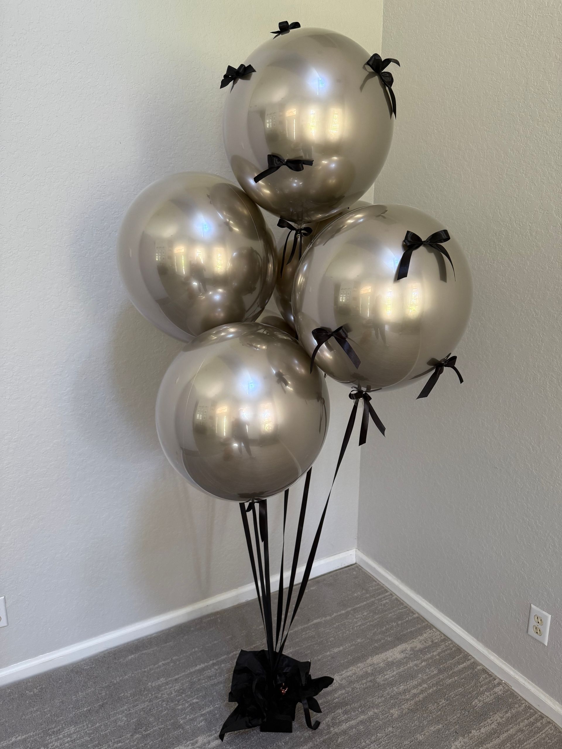 A bunch of pink balloons sitting on top of a wooden floor in a room.