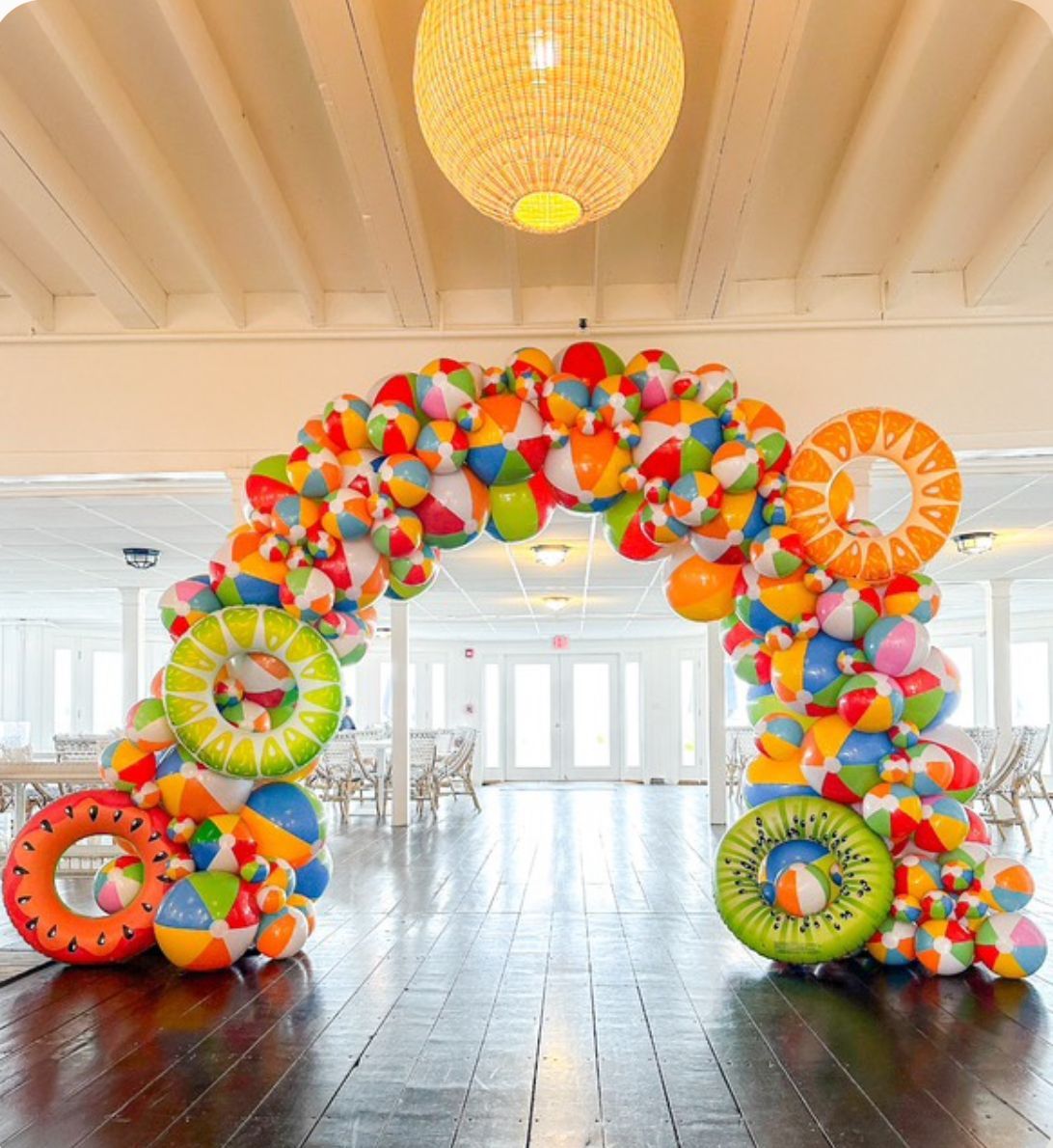 Colorful beach ball balloon arch and garland setup for a summer pool party featuring red, blue, yell
