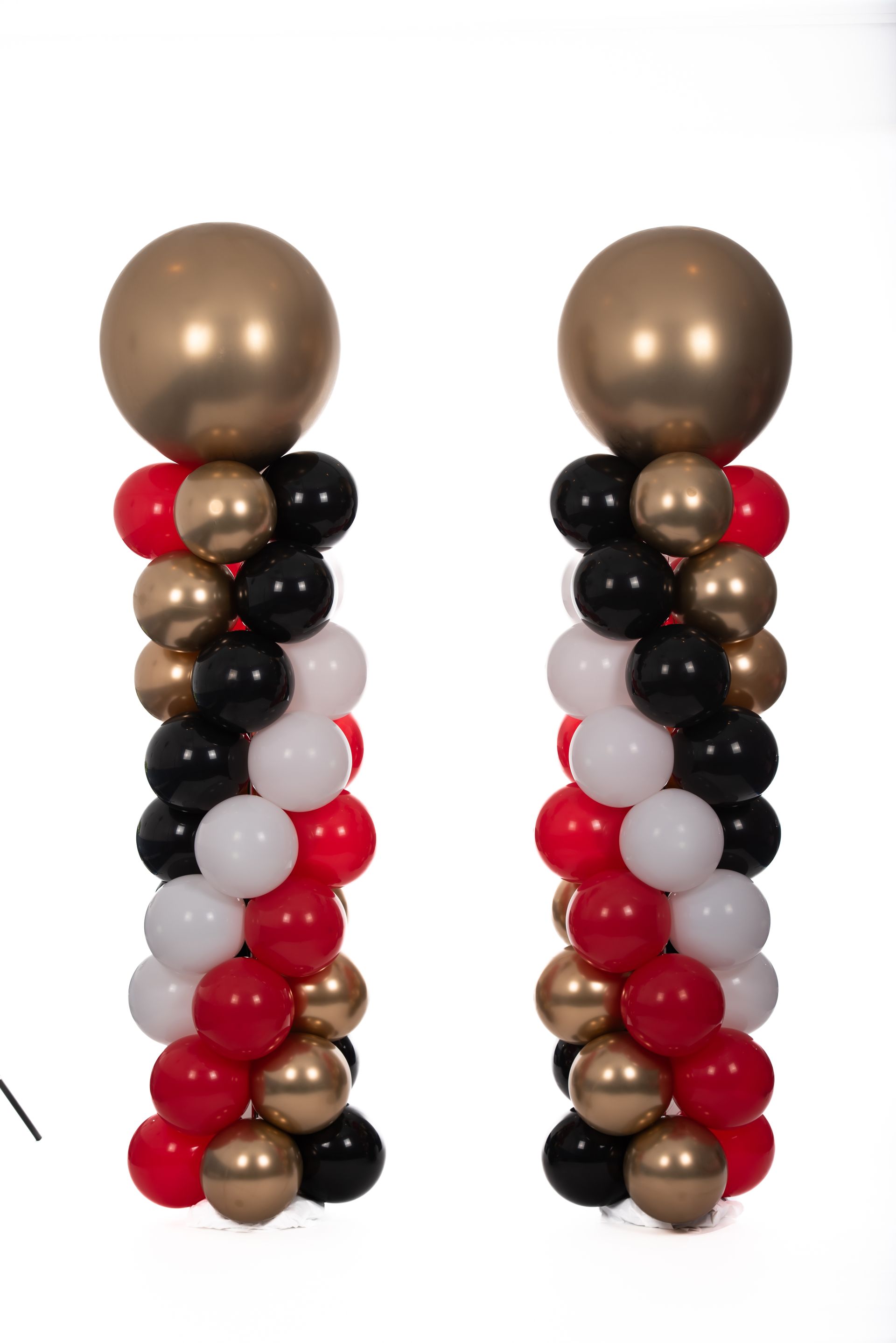Two columns made of red , black , and gold balloons on a white background.