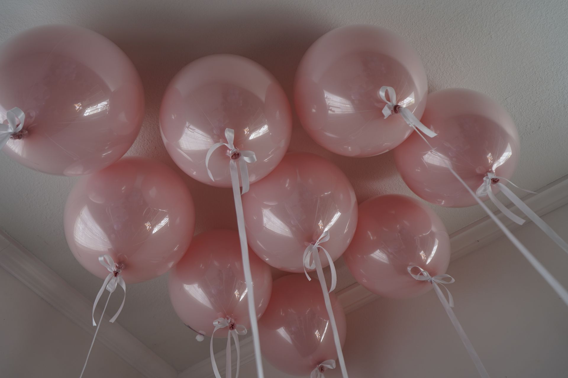 A bunch of pink balloons hanging from the ceiling
