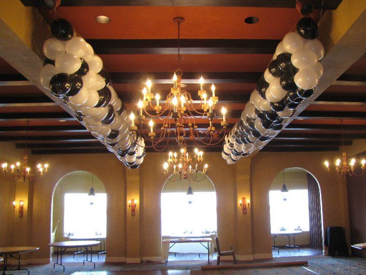A room with a chandelier and balloons hanging from the ceiling