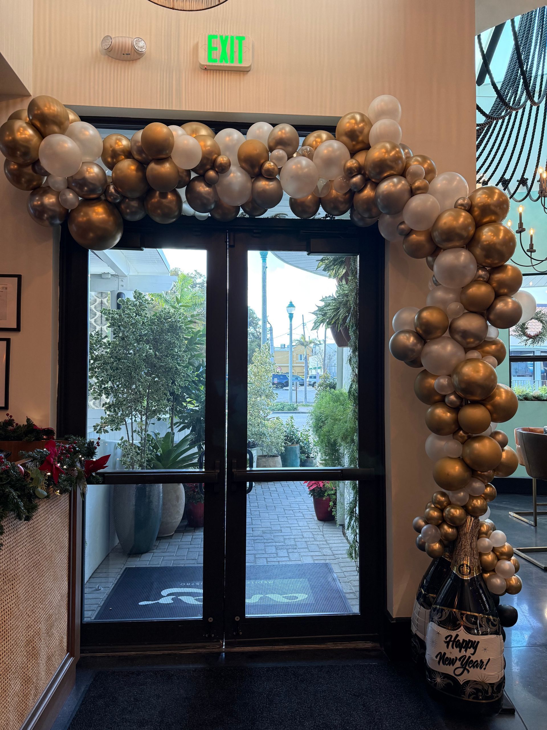 A bottle of champagne is surrounded by balloons in front of a door.