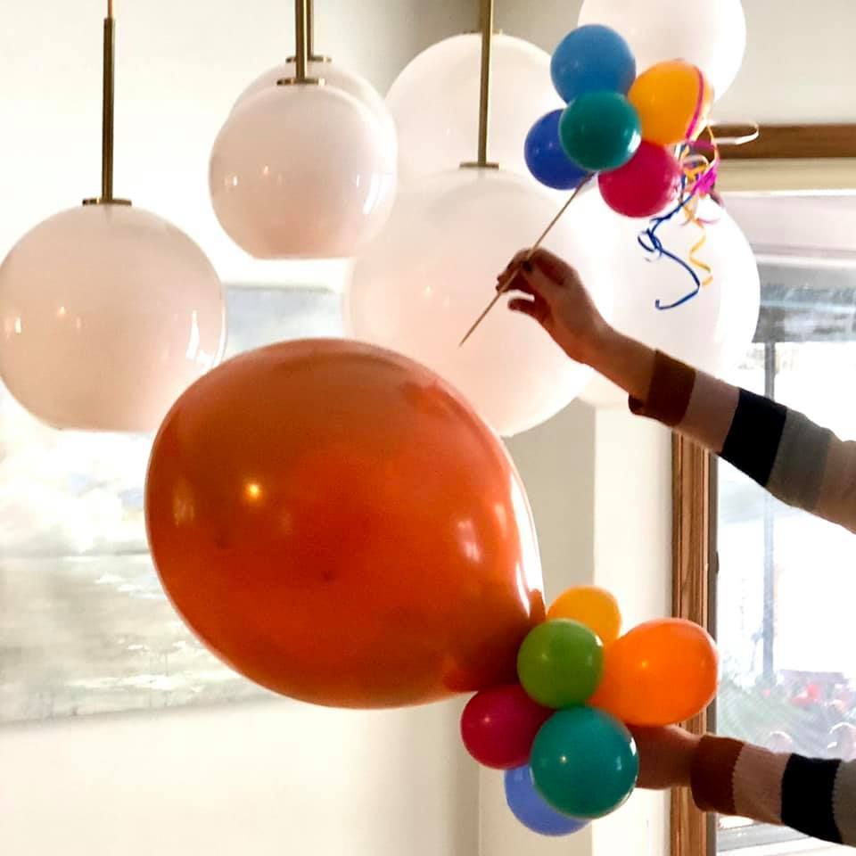 A person is holding a bunch of balloons in their hands