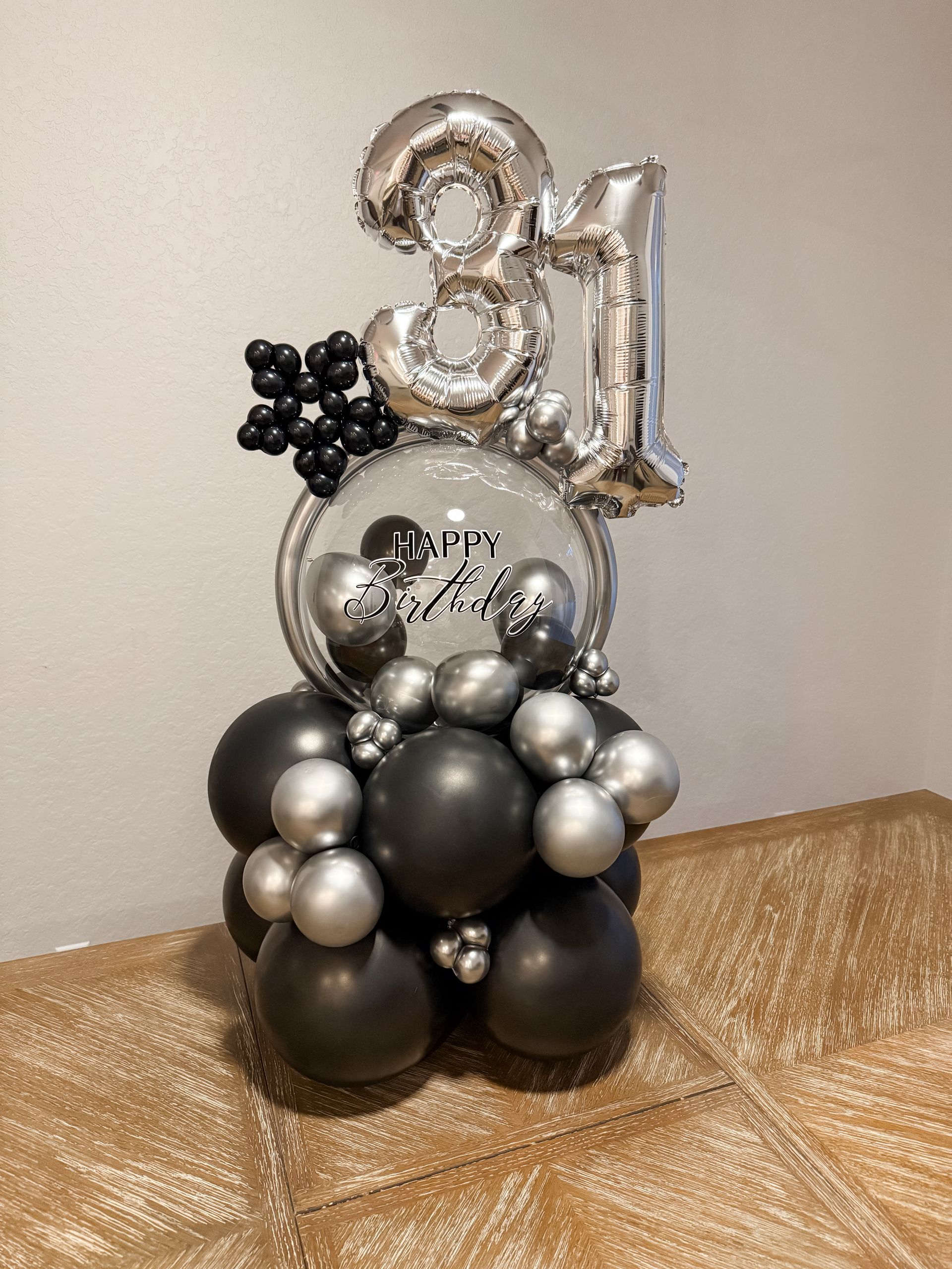 A bunch of black and silver balloons are sitting on top of a table.