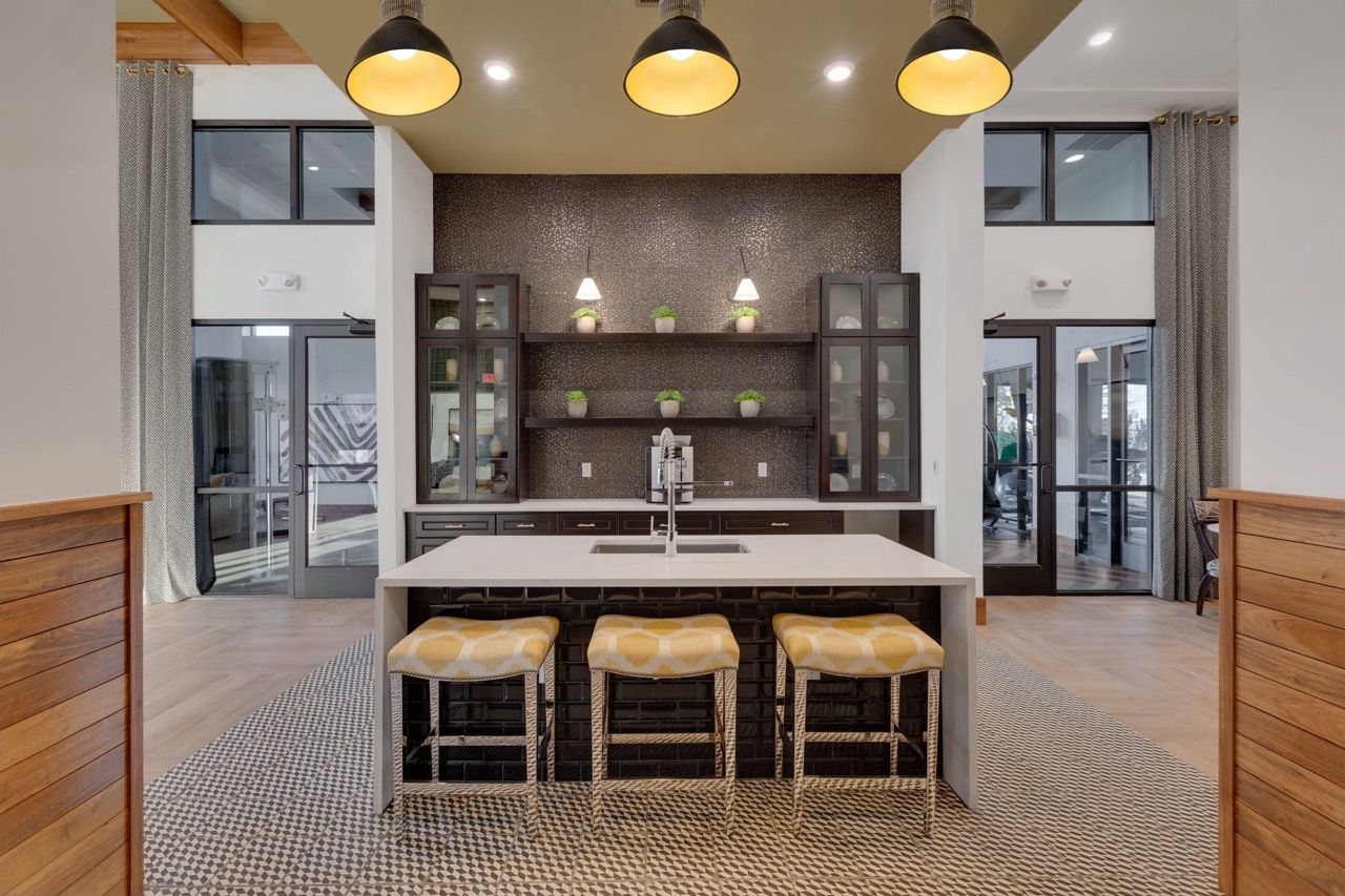 Modern community kitchen with island, pendant lights, and bar stools.