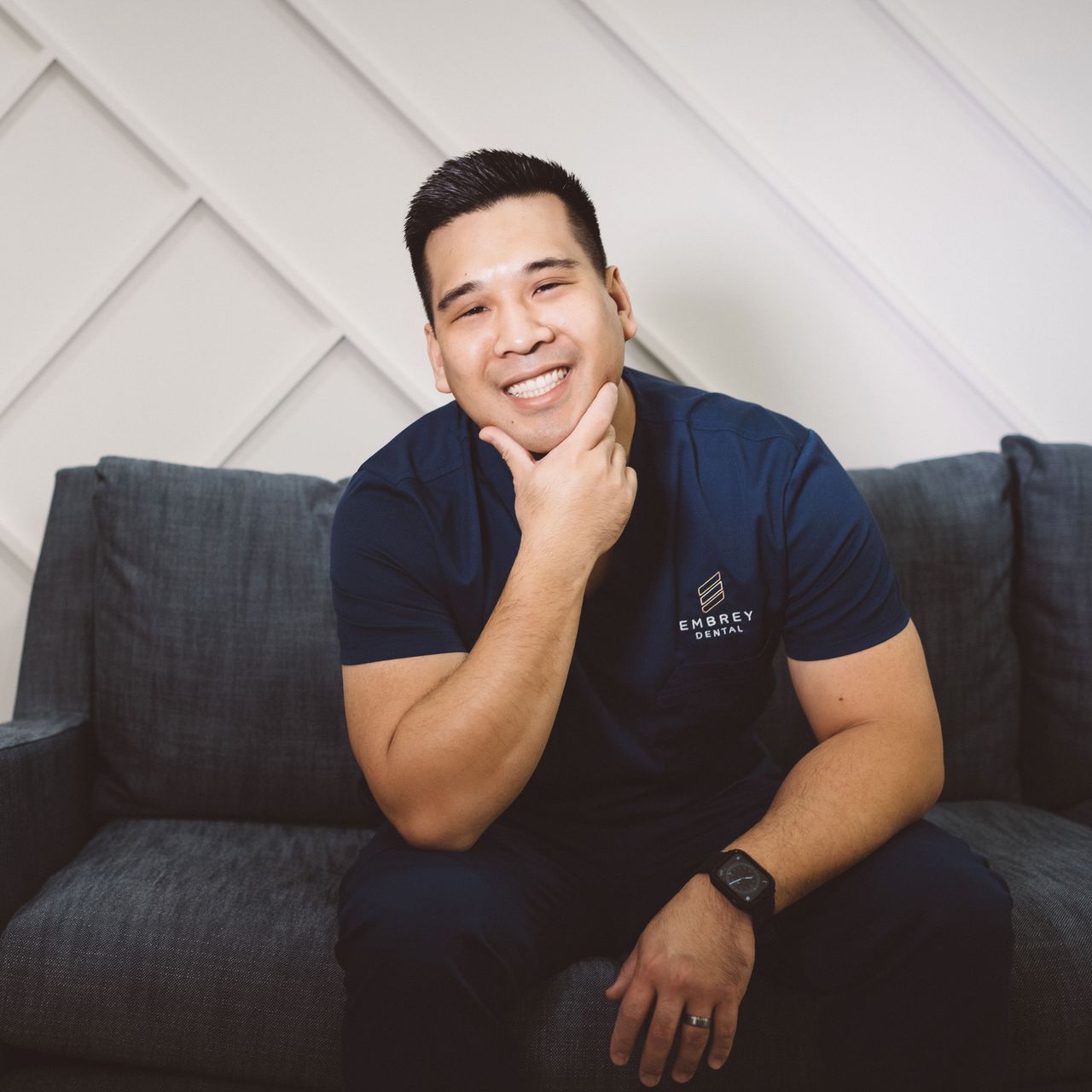 dr peter lim dentist smiling while sitting on couch in dental office