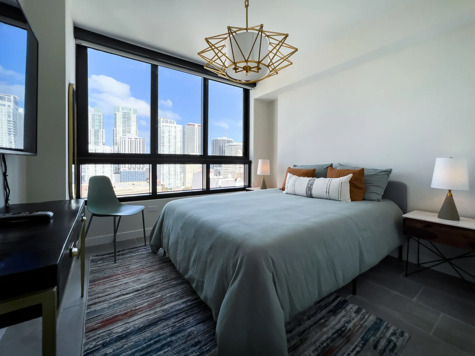 Modern bedroom with a large window wall and city views.