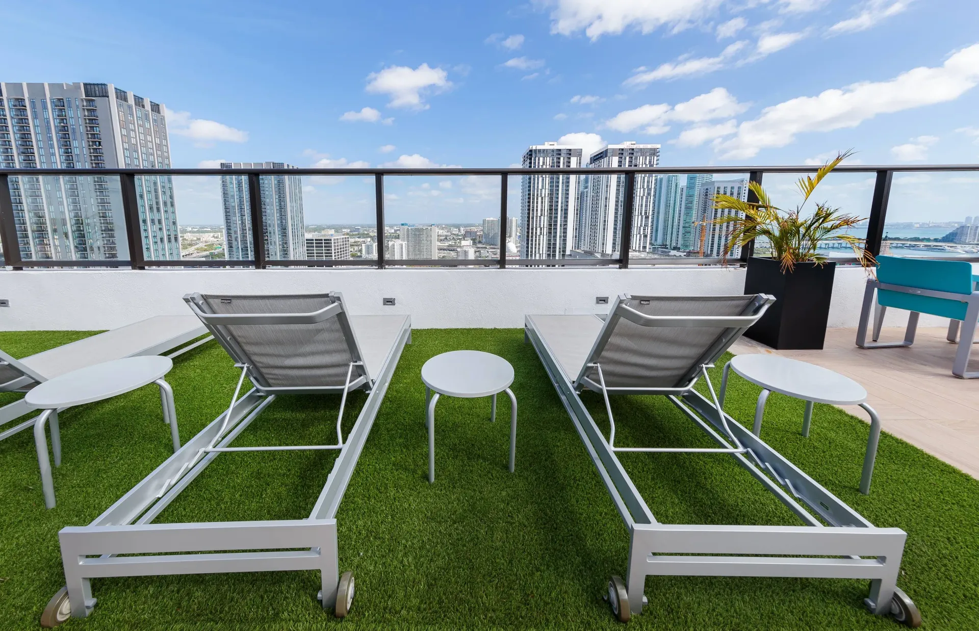 Rooftop terrace with lounge chairs, tables, and city skyline view.