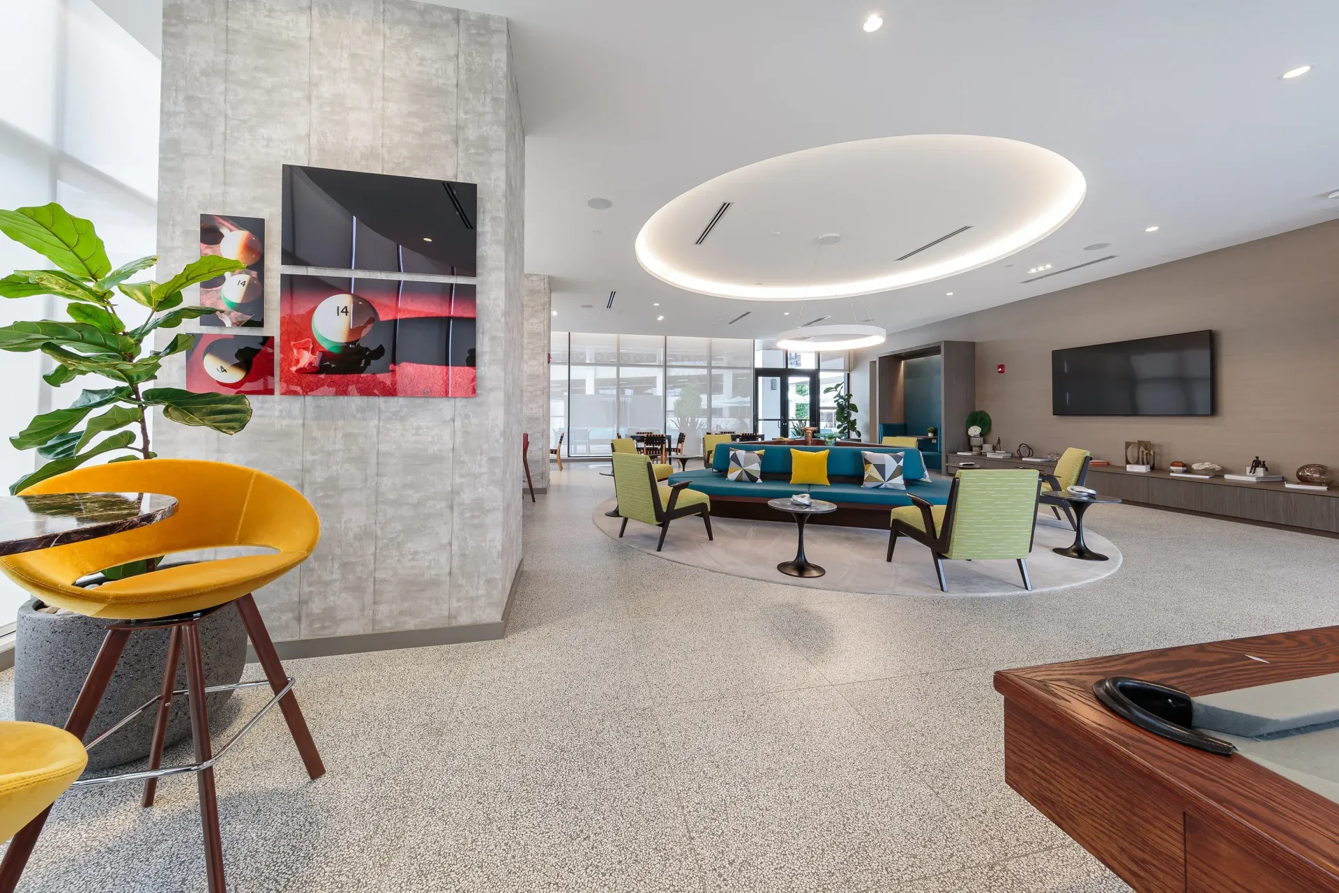 Modern apartment lobby with colorful seating, TV wall, and circular ceiling lighting.