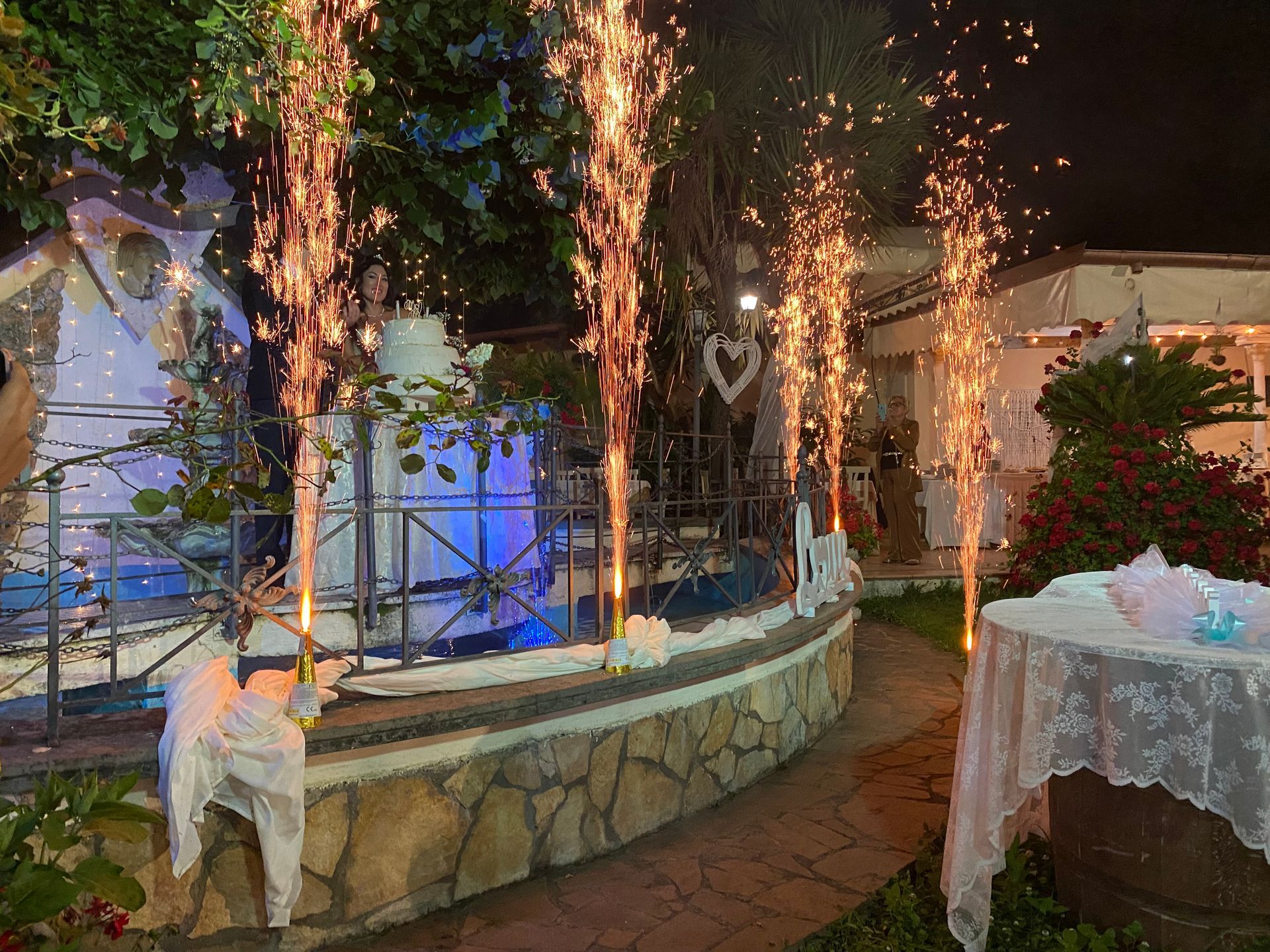 Ricevimento di nozze con stelle filanti, torta e area esterna decorata di notte.