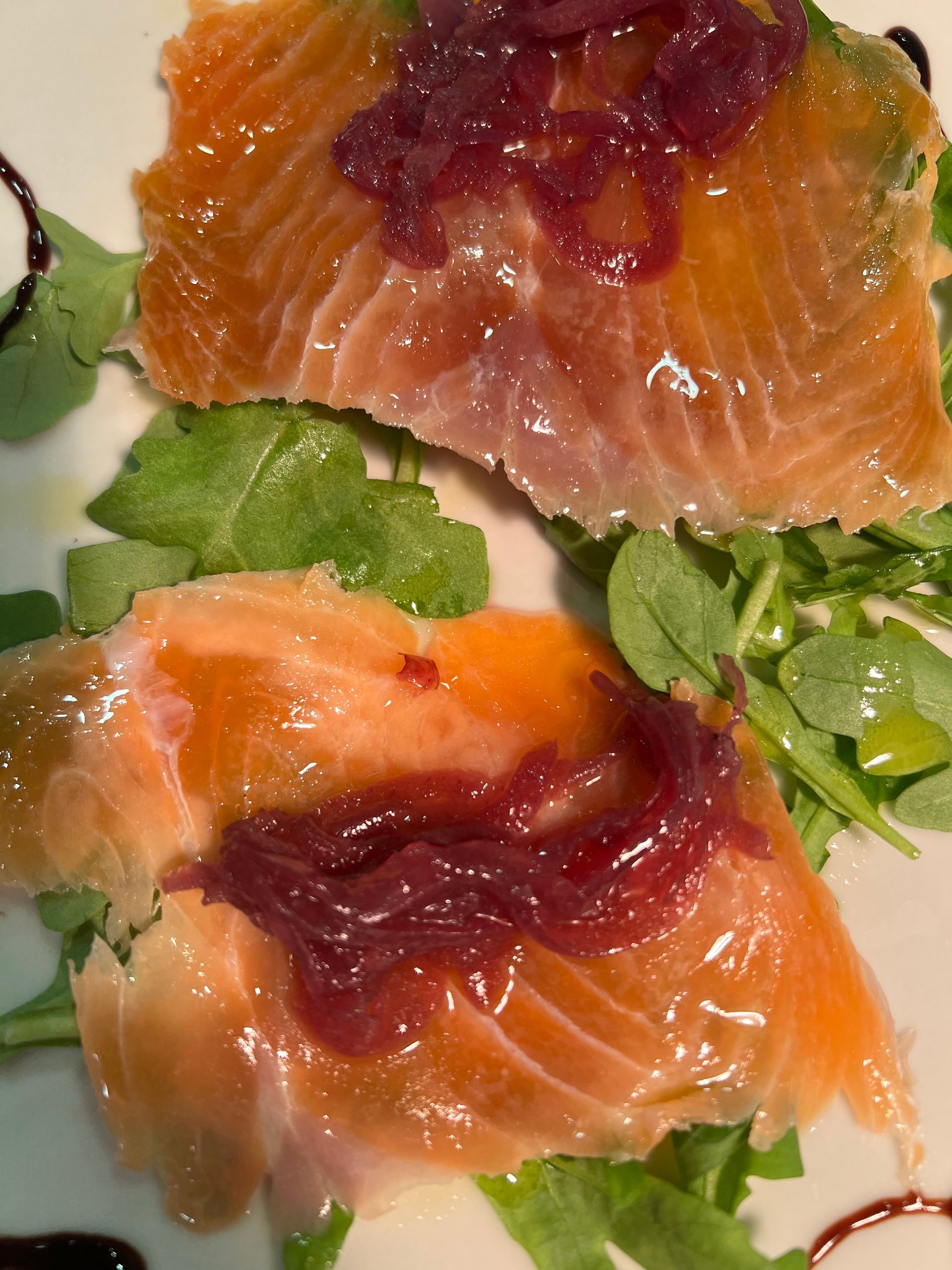 Salmone affumicato con cipolla rossa su un letto di rucola e glassa di aceto balsamico.