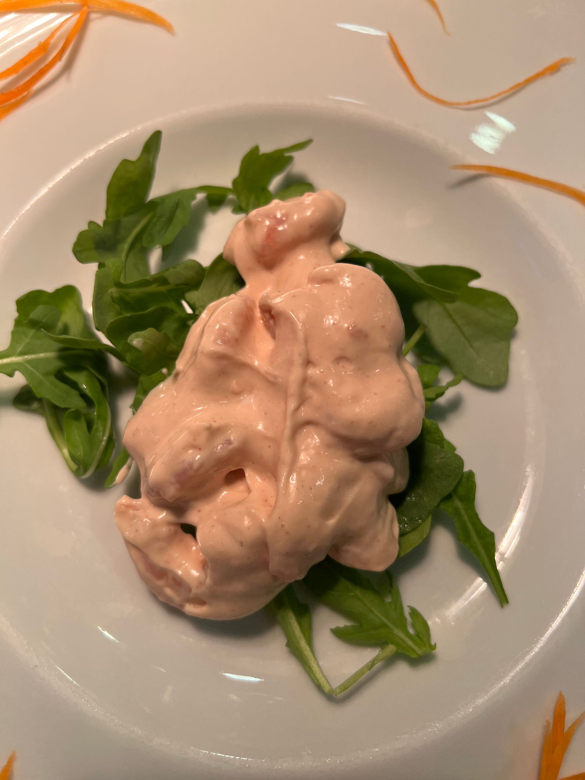 Insalata di mare rosa con rucola su un piatto bianco.