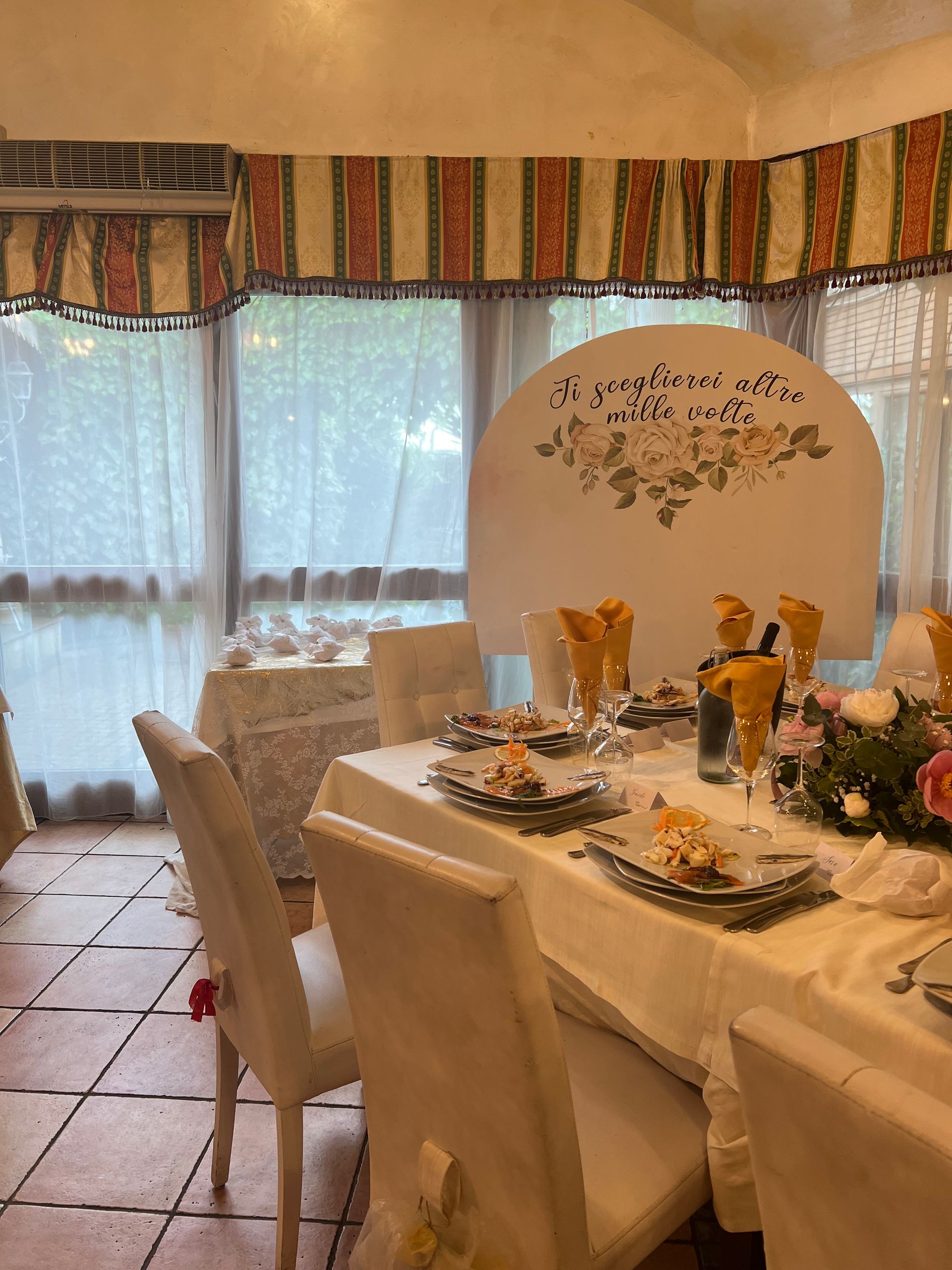 Sala da pranzo formale con tovaglie bianche, apparecchiata con decorazioni e composizioni floreali.