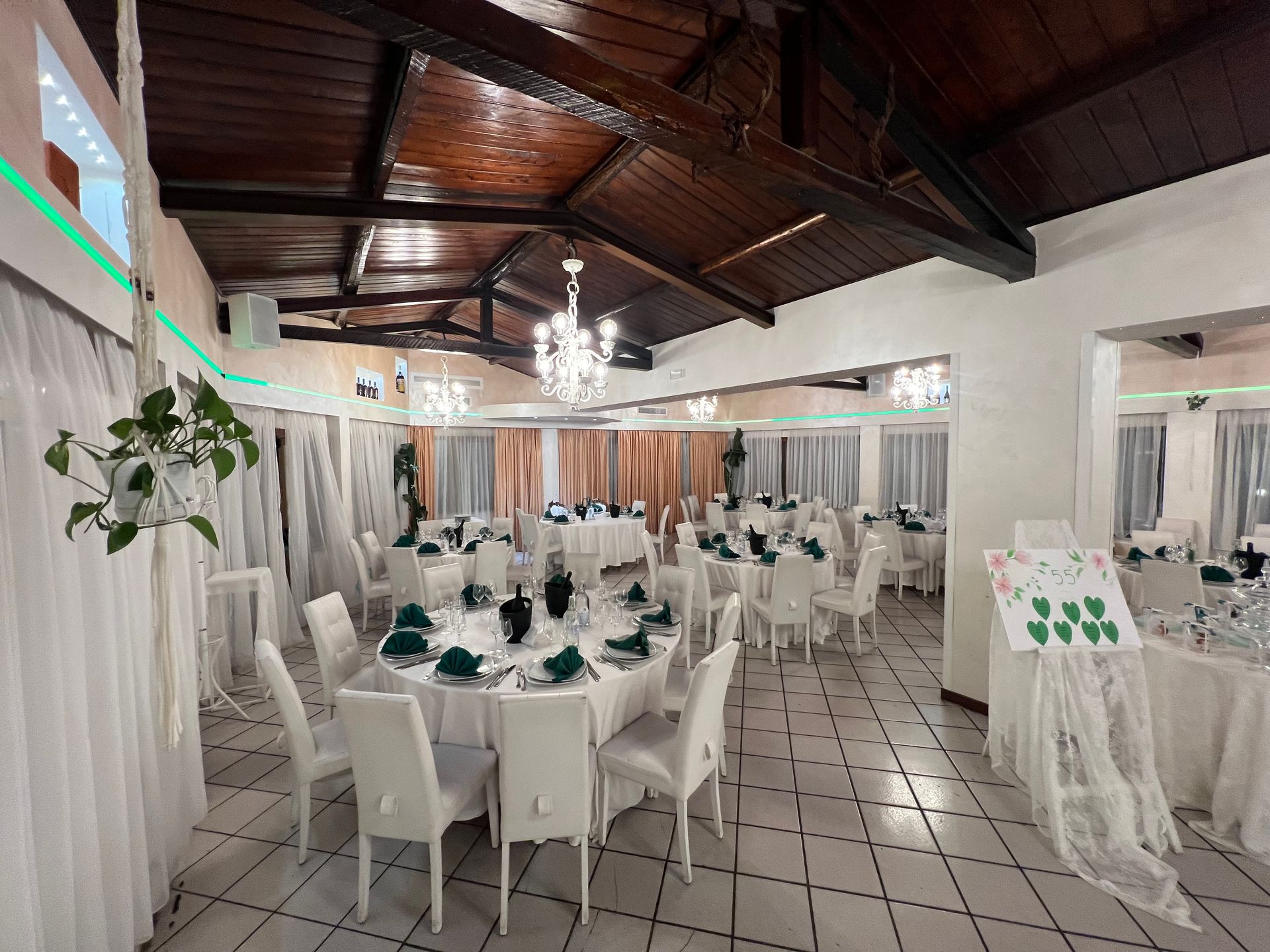 Sala per ricevimenti nuziali con tavoli, sedie e decorazioni bianche.