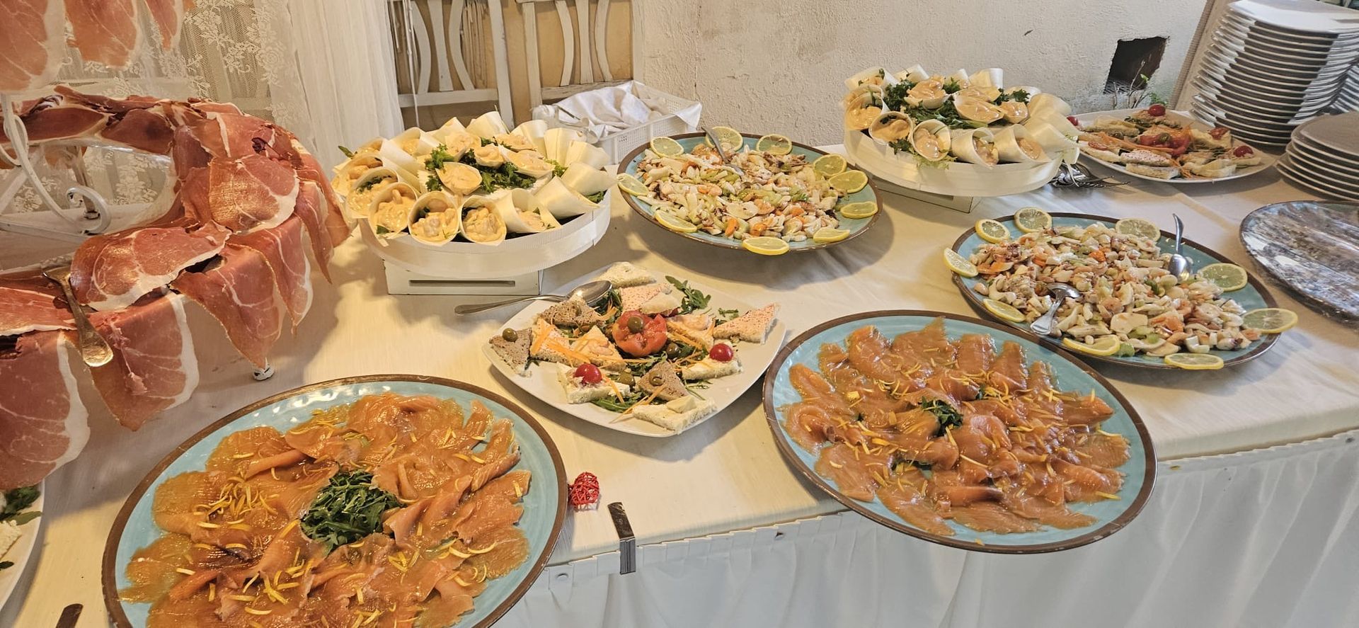 Tavolo da buffet con prosciutto, insalate e formaggi, allestito per una riunione.
