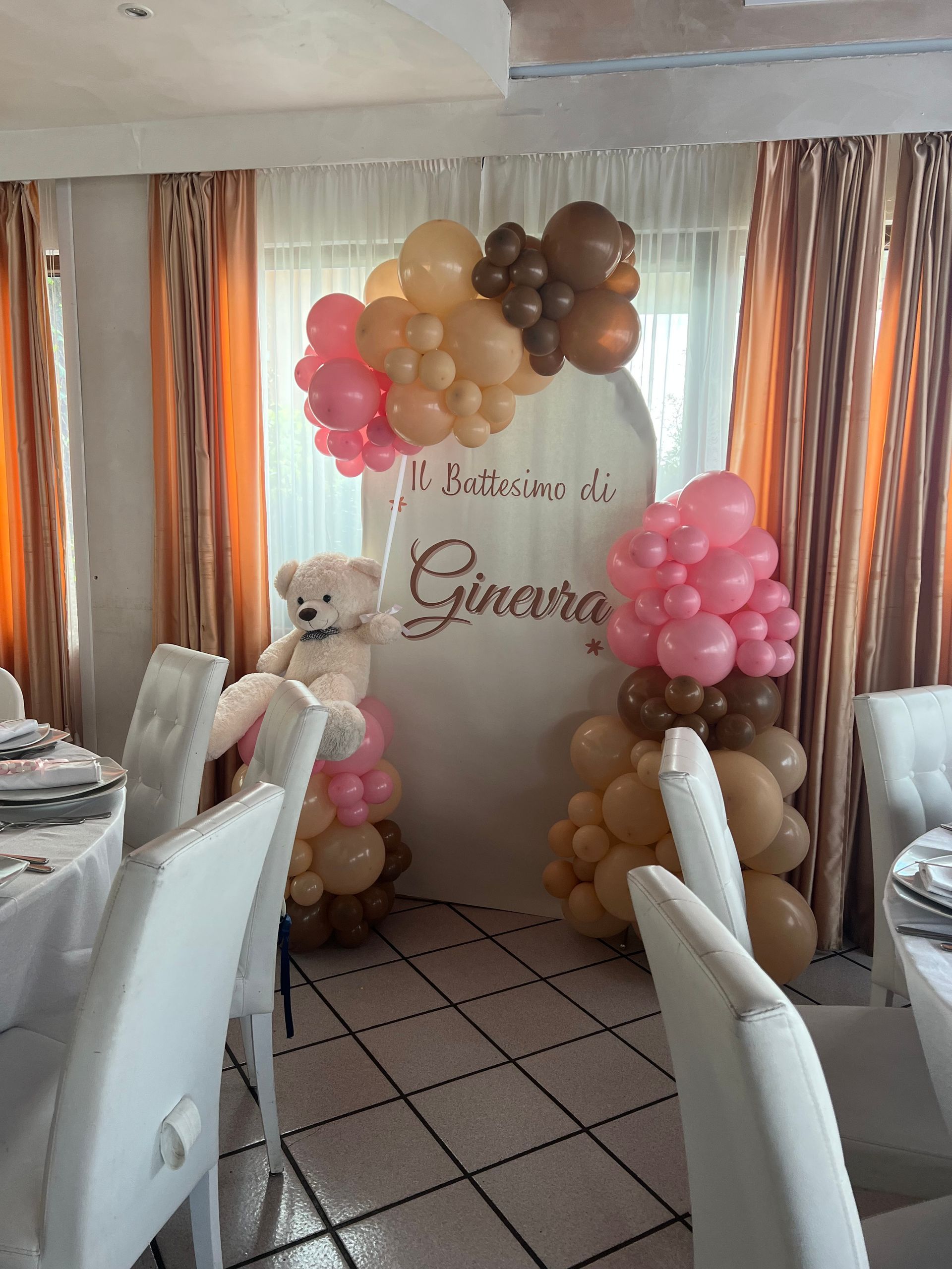 Decorazioni per la festa: composizioni di orsacchiotti e palloncini nei toni del marrone, rosa e beige su uno sfondo bianco, circondati da tavoli e sedie.