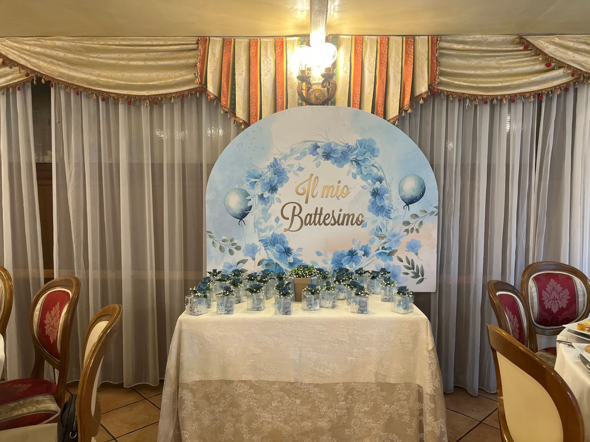 Tavolo decorato con sfondo per la celebrazione di un battesimo, con decorazioni blu e bianche.
