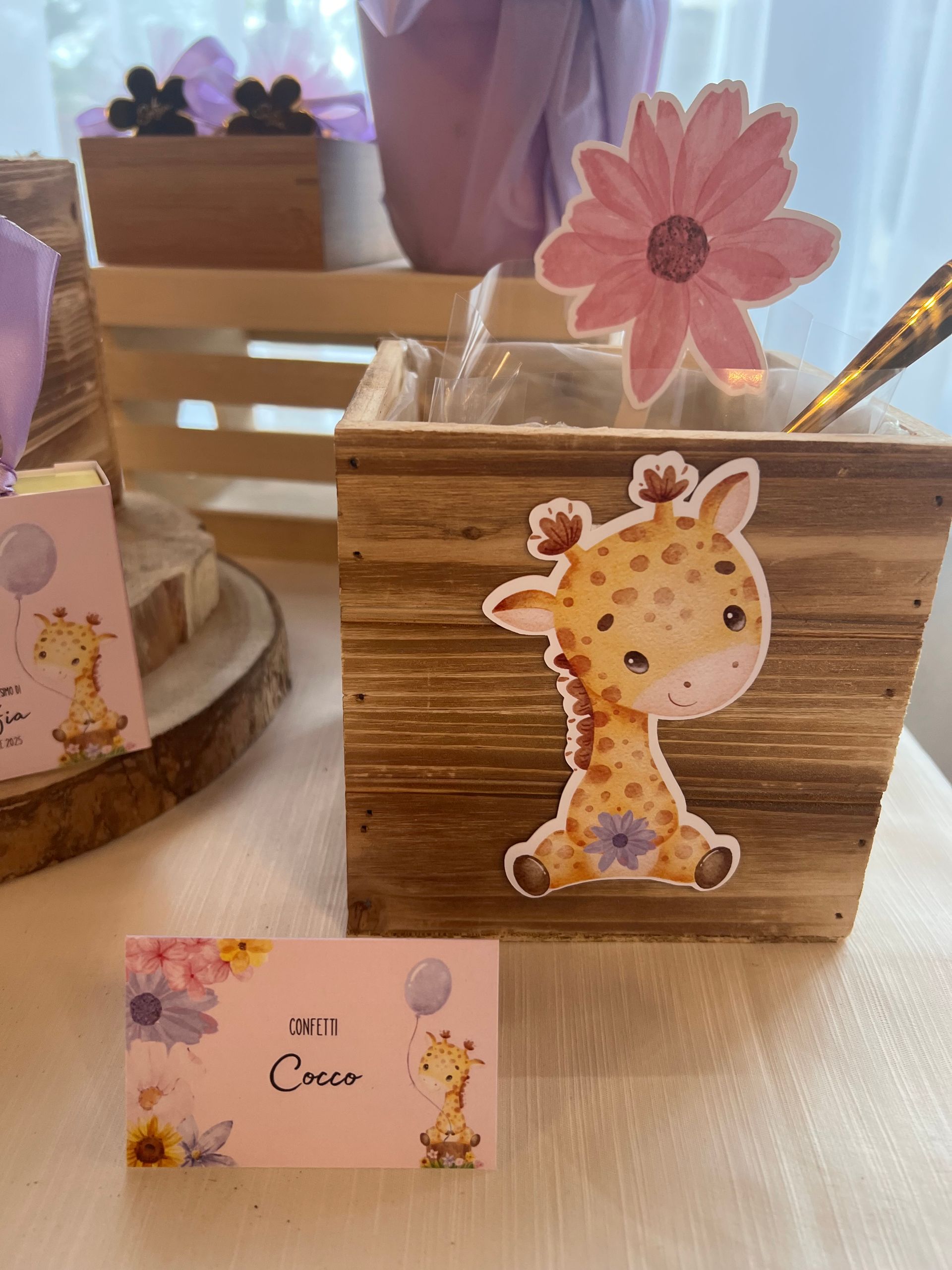 Scatola di legno con adesivo a forma di giraffa, fiore, cucchiaio e biglietto da visita per