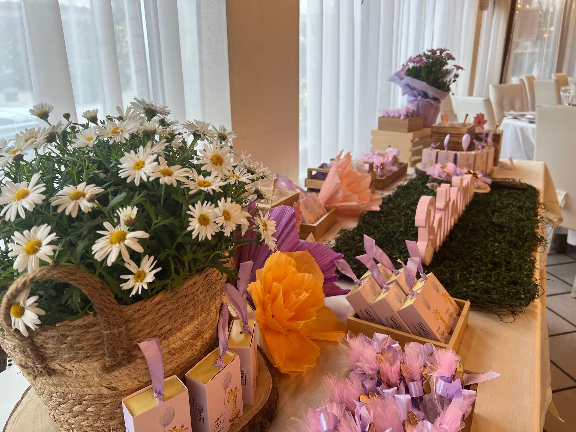 Un tavolo decorato con margherite, dolcetti e regali per un evento a tema floreale.