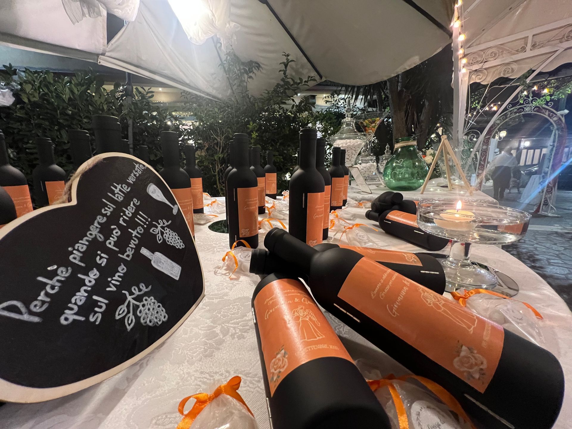 Bottiglie di vino su un tavolo, con un cartello a forma di cuore sulla lavagna e decorazioni.