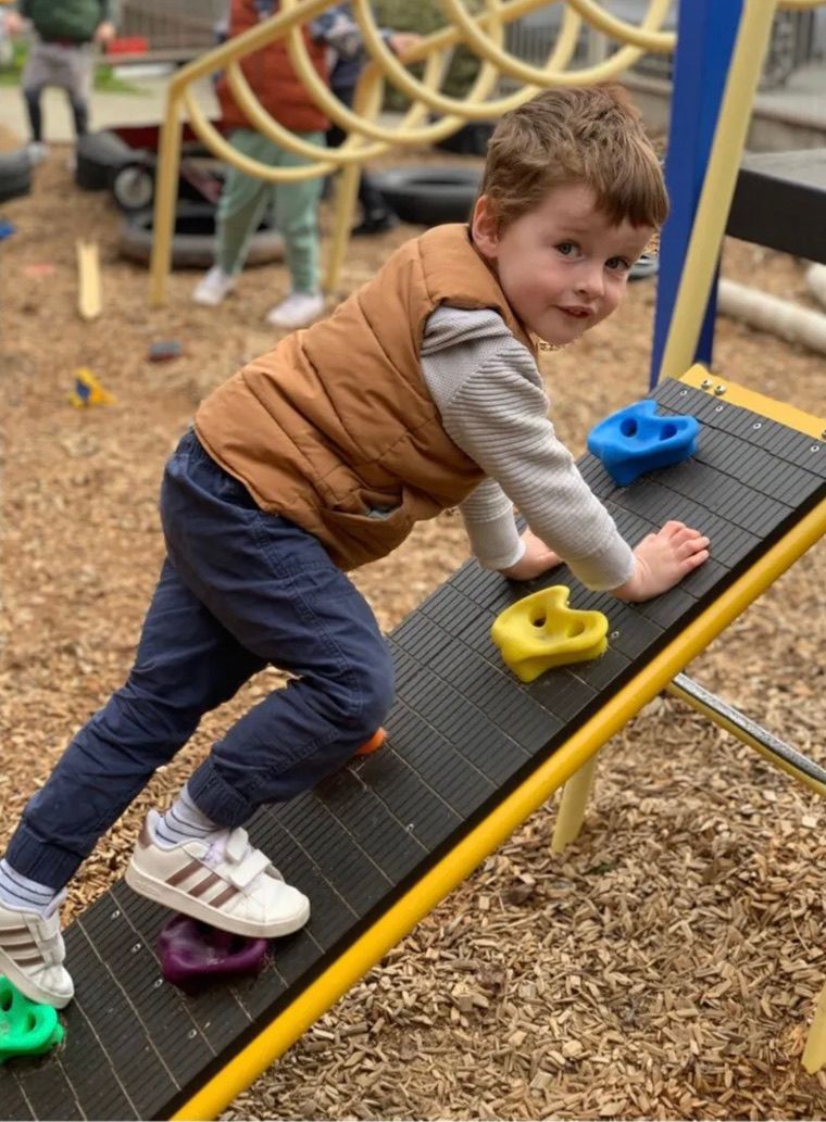 Smiling toddler plays with a colorful activity center indoors.