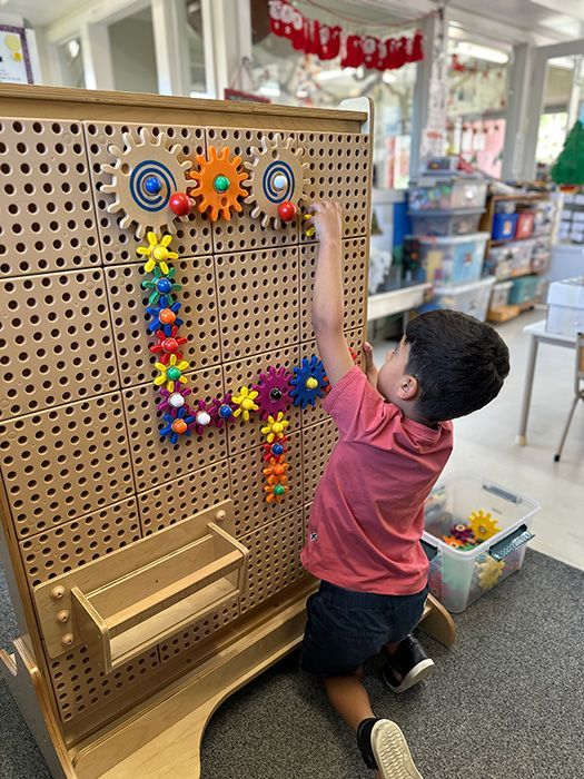 Baby crawling through a Winnie the Pooh play tunnel, looking forward with a smile.