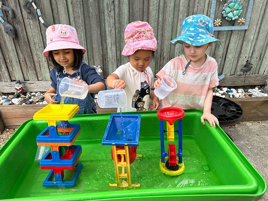 Child looking in a mirror at a table, smiling. Bright colors.