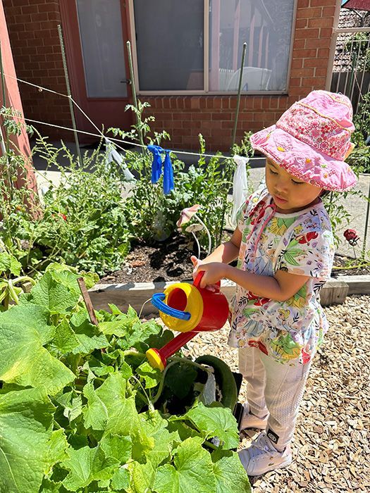 Young child climbing a black and yellow climbing wall with colorful handholds.