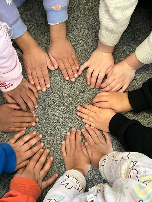 Two children playing with colorful wooden toys at a table. One child holds a purple cone.