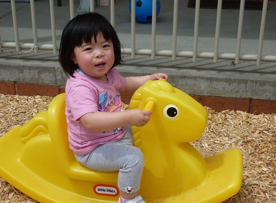 Boy in a firefighter costume looking out of a yellow play structure.