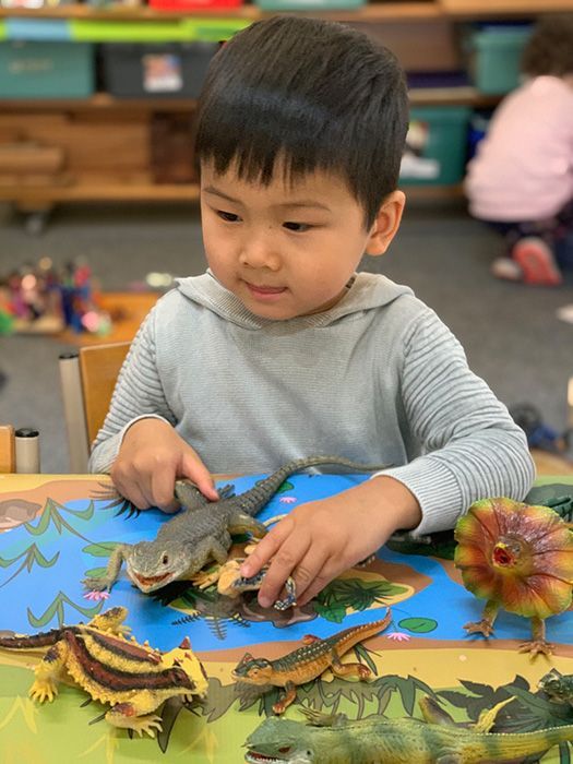 Young child interacting with a light table, placing colorful shapes on it.