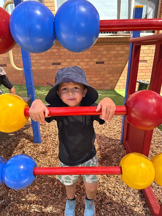 Young child climbing a black and yellow climbing wall with colorful handholds.